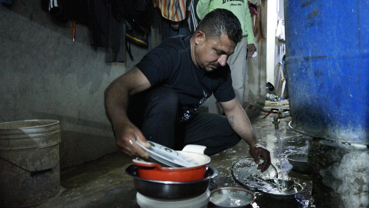 زهير يقوم بغسل الأواني على الأرض، بسبب عدم توفر مطبخ للطهي