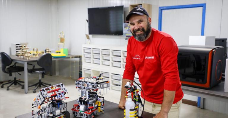 لاجئون سوريون في مخيم الزعتري، يبتكرون إنسانا آليا لتوزيع المعقم أوتوماتيكيا. مدرب الروبوتكس في مخيم الزعتري مروان الزعبي وامامه على الطاولة الانسان الآلي لتعقيم اليدين (عمان نت)