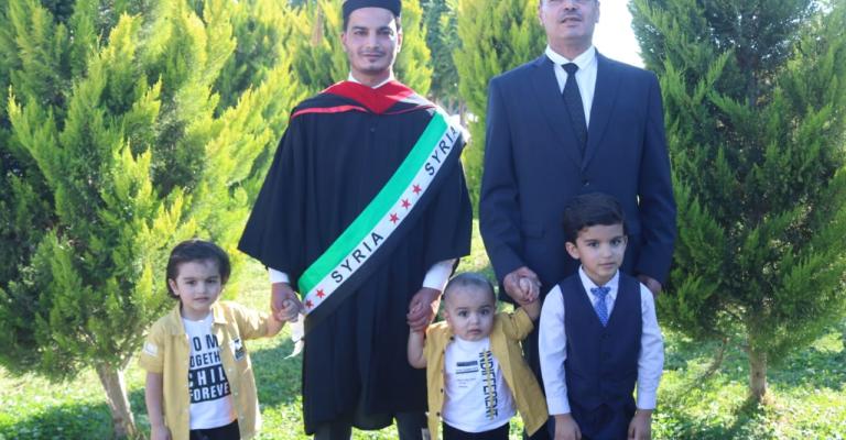 طالب سوري ينال مرتبة الشرف على أقرانه بتخصص الصحافة في اليرموك ضمن فوج المئوية عبد الرحمن زين العابدين، إلى جانبه والده وأطفاله الثلاثة