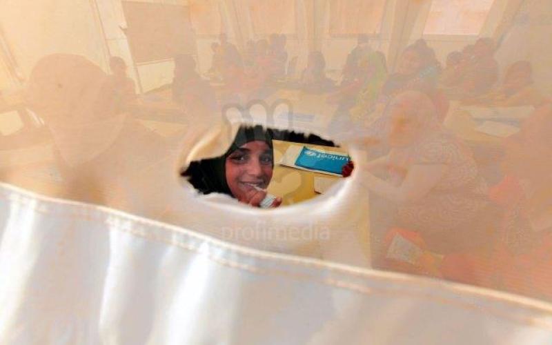 طفلة في الزعتري تنظر من ثقب الخيمة