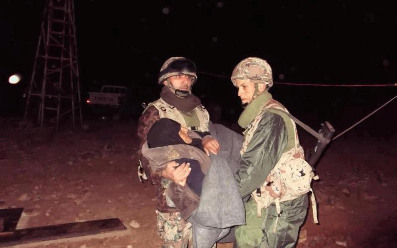 جنود أردنيين يحملون لاجئة مسنة