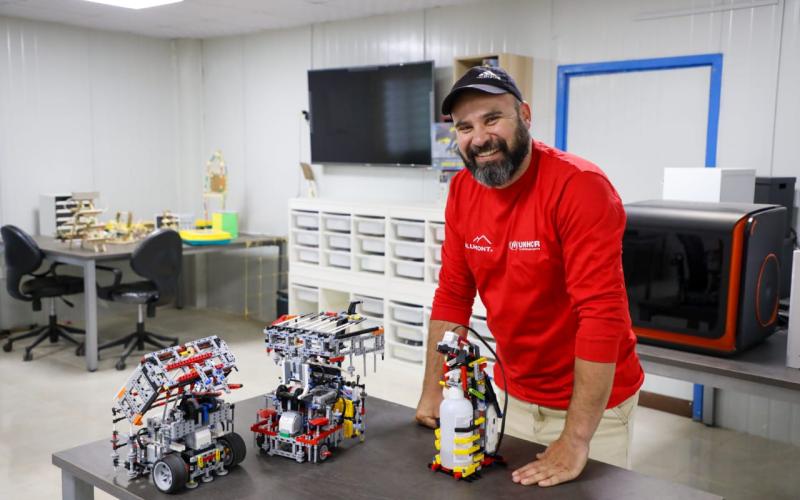 مدرب الروبوتكس في مخيم الزعتري مروان الزعبي وامامه على الطاولة الانسان الآلي لتعقيم اليدين (عمان نت)